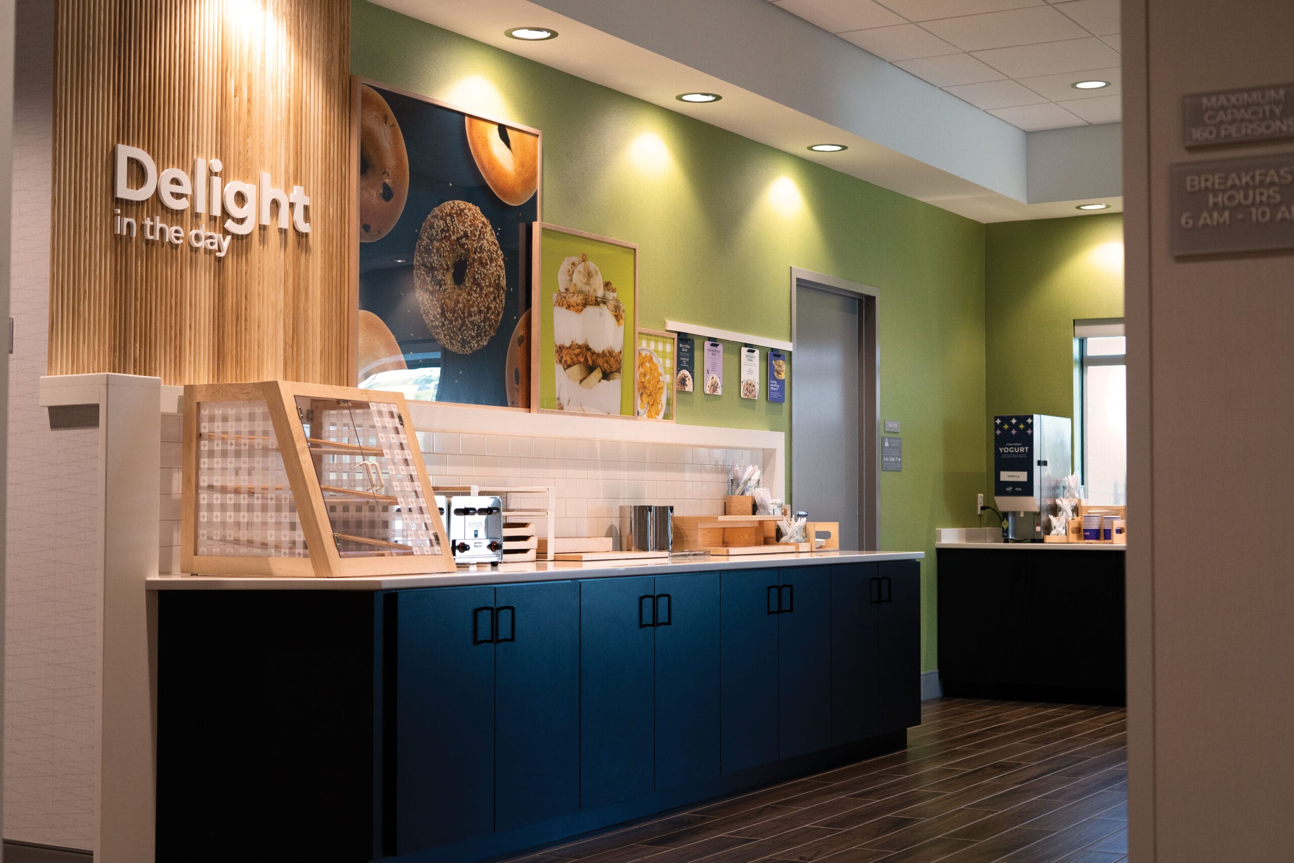 Modern breakfast area featuring a dark blue counter, food displays, and vibrant green walls with food images.