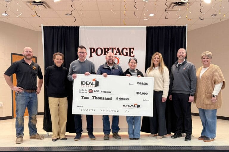 Group of seven people holding a large check for $10,000, celebrating a donation to ACE Academy in Portage.